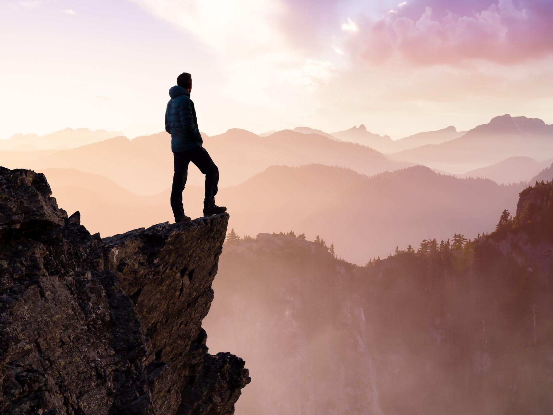 A person looking across mountain peaks at sunrise